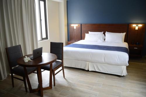 a bedroom with a bed and a table with a laptop at Hotel San Agustin Plaza in Latacunga