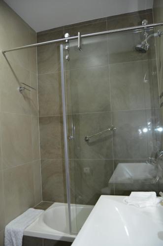a bathroom with a glass shower with a sink and a tub at Hotel San Agustin Plaza in Latacunga
