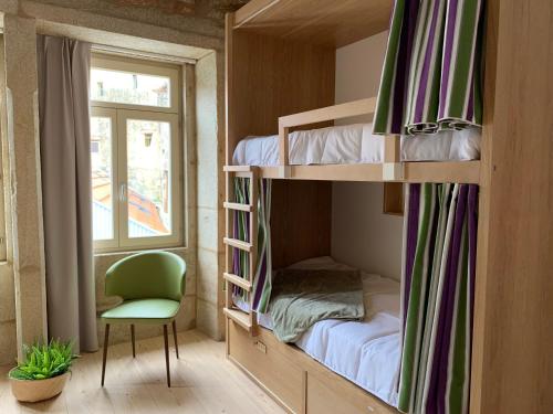 a room with bunk beds with a chair and a window at Lost Inn Porto Hostel in Porto