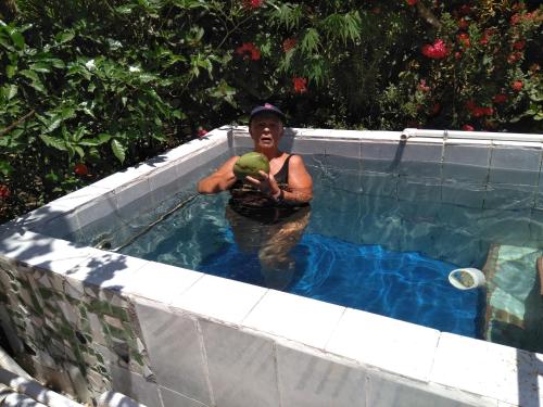 a man holding an apple in a swimming pool at chambre indépendante chez l'habitant in Parrita