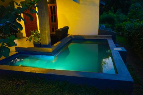 a swimming pool in the yard of a house at night at Hidden Lake Cottages Sigiriya in Sigiriya
