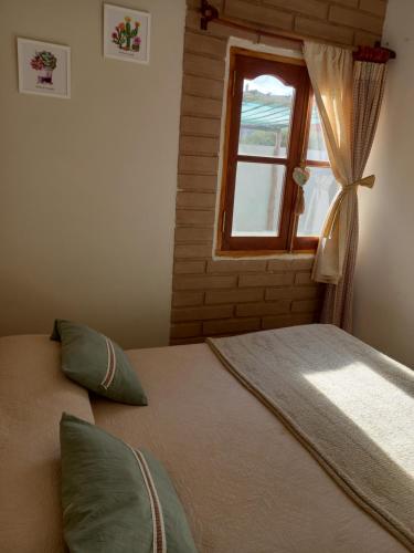 1 dormitorio con cama y ventana en cabaña merlot en Cafayate