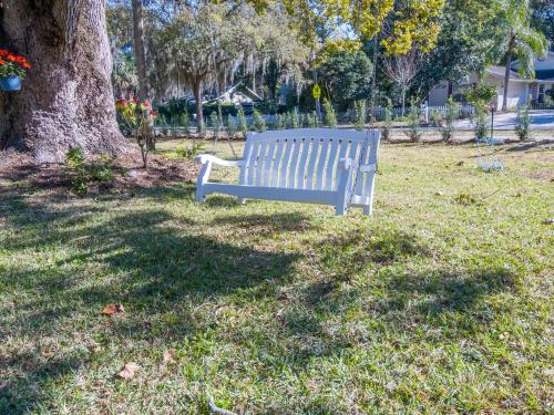 a white bench sitting in the grass under a tree at The Estate at Mt Dora in Mount Dora