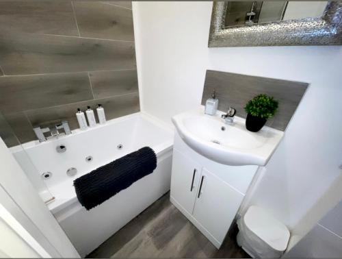 a white bathroom with a sink and a bath tub at Albert Hottub & Jacuzzi Apartments in Blackpool