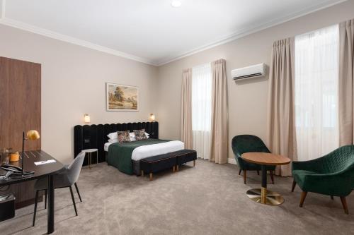 a hotel room with a bed and a desk and chairs at Mount Gambier Hotel in Mount Gambier