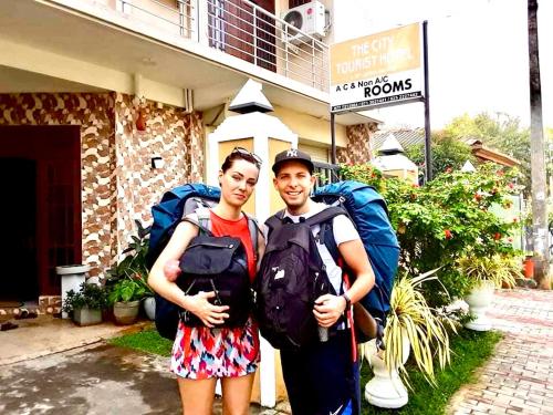 two people with backpacks standing in front of a building at The City Tourist Hotel in Anuradhapura