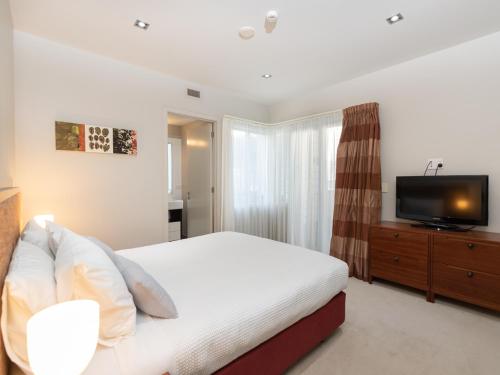a bedroom with a bed and a flat screen tv at Oceanside - Paihia Waterfront Apartment in Paihia