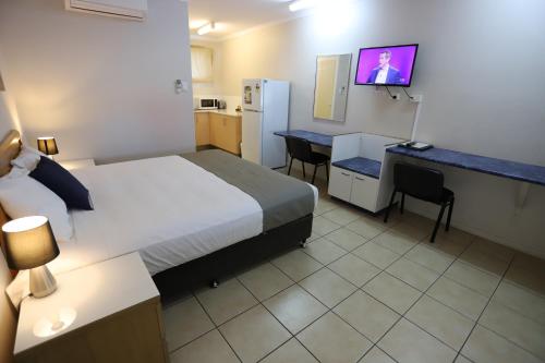 a hotel room with a bed and a desk and a television at Tropic Coast Motel in Mackay