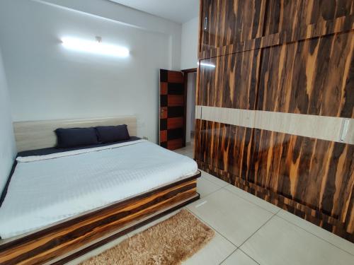 1 dormitorio con 1 cama y pared de madera en SS LUXURY Comforts-Two bedroom en Chikmagalūr