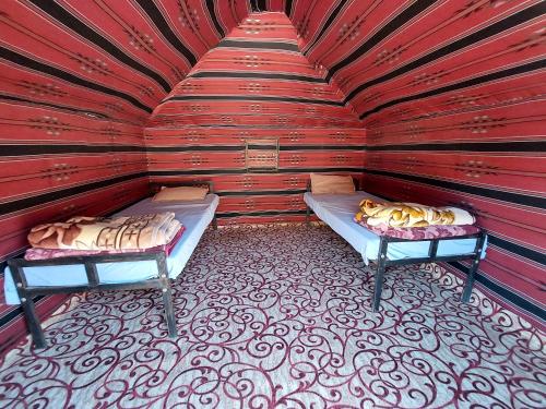 um quarto com duas camas numa parede vermelha em bedouin future camp em Wadi Rum