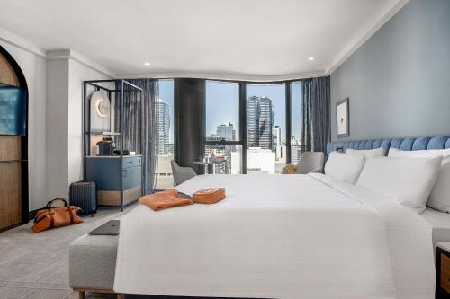 a large white bed in a room with a large window at voco Melbourne Central in Melbourne
