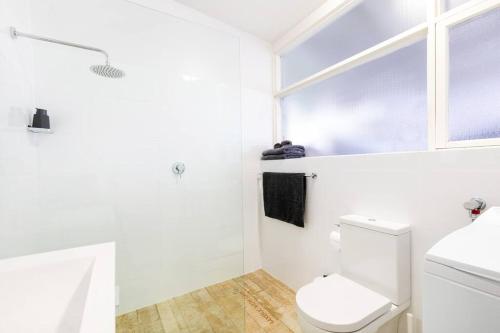 baño blanco con aseo y ventana en Modern Stylish Self-contained Studio Apartment en Burnside