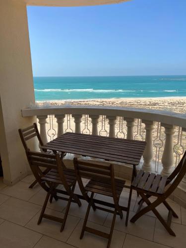 a table and chairs on a balcony with the beach at Newly renovated Gulf Studio With Gym beach pool Access in Ras al Khaimah