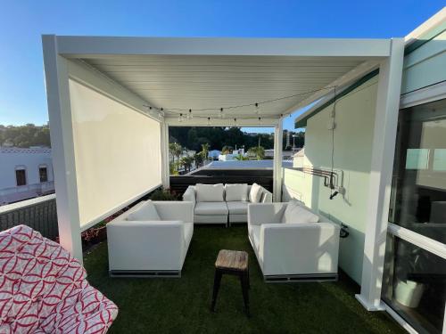 un patio con sofás blancos, una cama y una mesa en Laneway Apartments en Napier
