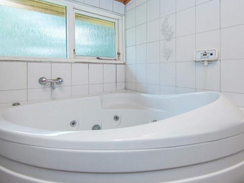 a white bath tub in a bathroom with a window at 7 person holiday home in Grenaa in Grenå