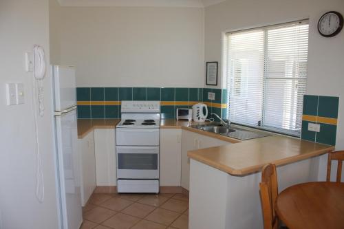a kitchen with a stove a sink and a refrigerator at Illawong Beach Resort in Mackay
