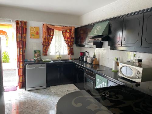 a kitchen with black cabinets and a washer and dryer at Villa Dreamteam in Flic-en-Flac