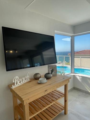 a large flat screen tv on a wall with a table at Whale Rock in Cape Town