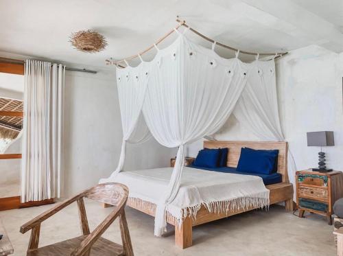 a bedroom with a canopy bed with blue pillows at Rock'n Reef in Uluwatu