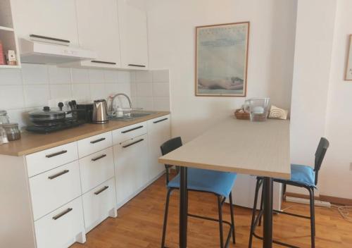 a kitchen with white cabinets and a table and chairs at Studio Room Ensuite by the Beach, Entire Independent Unit in Limassol
