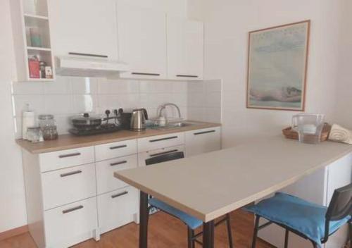 a kitchen with white cabinets and a table and chairs at Studio Room Ensuite by the Beach, Entire Independent Unit in Limassol
