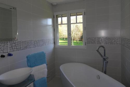 La salle de bains blanche est pourvue d'une baignoire et d'un lavabo. dans l'établissement Cottage, Vinnerville, à Vinnemerville