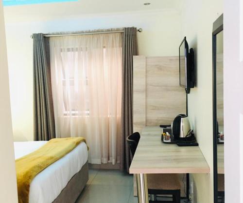 a hotel room with a bed and a desk with a television at Classy Guest House in Johannesburg
