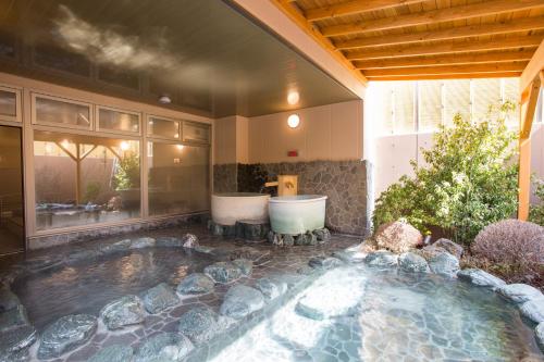 a swimming pool with two bath tubs in a yard at Sun Plaza Hotel Fuji Lake Yamanaka in Yamanakako