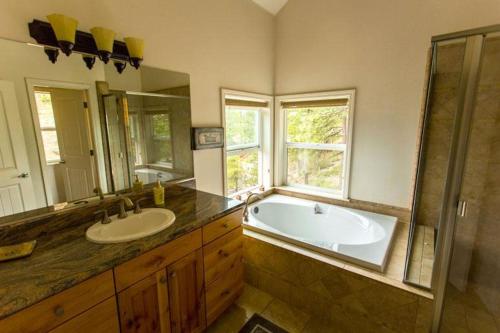 Un baño con bañera, lavabo y espejo. en Birds Eye Vista, en Yosemite West