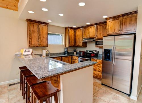 a kitchen with wooden cabinets and a stainless steel refrigerator at Alpine Aerie in Yosemite West
