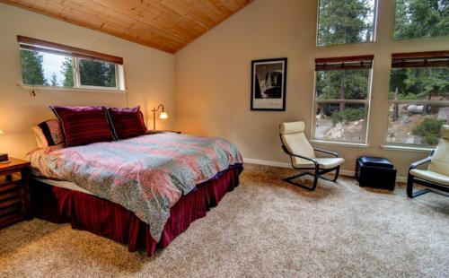 a bedroom with a bed and a chair and windows at Alpine Aerie in Yosemite West