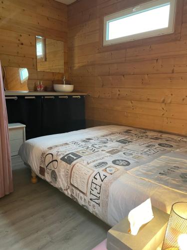ein Schlafzimmer mit einem Bett in einer Holzhütte in der Unterkunft Chez Stéphane et Emilie in Grenade-sur-Garonne