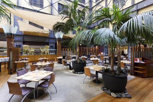 a restaurant with tables and chairs and palm trees at Sky Tower Serenity + Rooftop Pool in Auckland