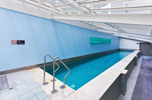 een zwembad in een gebouw met een blauwe muur bij Sky Tower Serenity + Rooftop Pool in Auckland