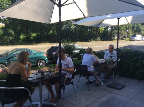 a group of people sitting at tables under an umbrella at Hotel Pension Oranje in Valkenburg