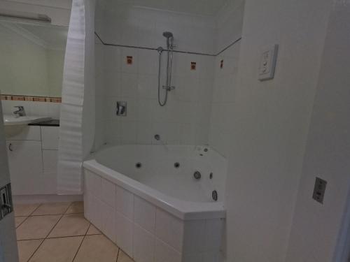 a white bathroom with a tub and a shower at Central Plaza Port Douglas in Port Douglas