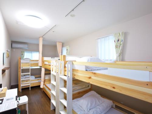 a room with three bunk beds and a desk at Shironoshita Guesthouse in Himeji