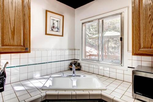 a white tiled bathroom with a sink and a window at Skyline Retreat in Yosemite West