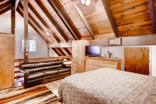 a bedroom with a bed and a couch and a television at Yosemite's Creekside Birdhouse in Wawona