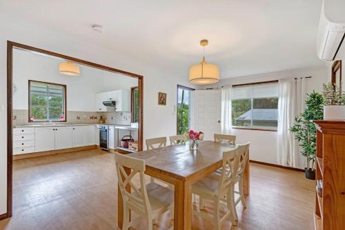 a kitchen and dining room with a wooden table and chairs at Divine Cottage - Main Street Bangalow in Bangalow
