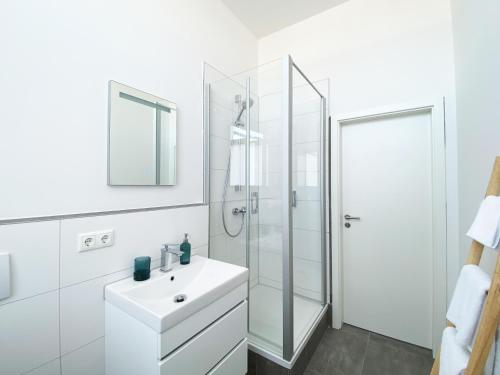 biała łazienka z umywalką i prysznicem w obiekcie Best Boarding House w mieście Hanau