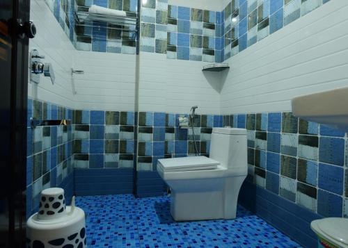 a bathroom with a toilet and blue tiled walls at ANNUS HOMESTAY RAMAKKALMEDU in Ramakkalmedu