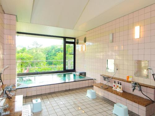 a large bathroom with a swimming pool and a window at Yumeno Onsen in Kami