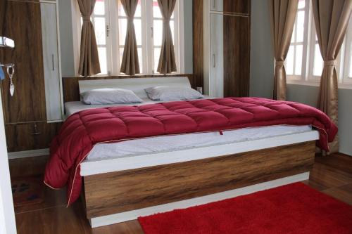 a large bed in a bedroom with a red rug at Saanidhya Sunset View Villa in Mukteswar