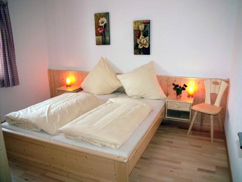 a bedroom with a bed with white sheets and two lamps at Gästehaus Weissenbauer in Lenggries