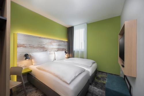 Habitación de hotel con cama y pared verde en ibis Styles Stuttgart Vaihingen en Stuttgart