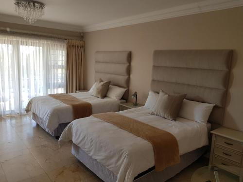 a bedroom with two beds and a large window at Winchester Place in Port Elizabeth