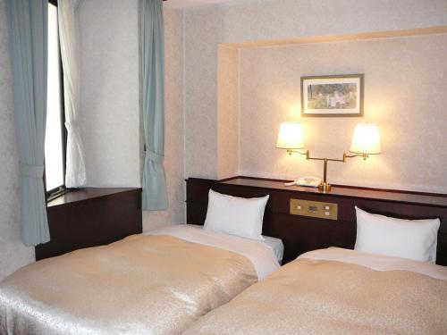 a hotel room with two beds and a window at Hotel Hanakomichi in Nara