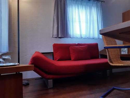 a red couch sitting in a room with a window at Schiefes Haus in Ulm