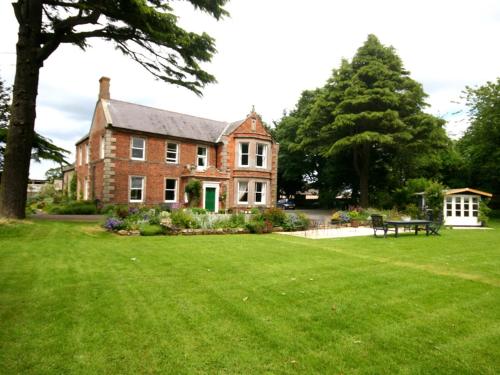 Cheswick的住宿－Broomhouse Farmhouse，一座带绿色草坪的大型砖屋